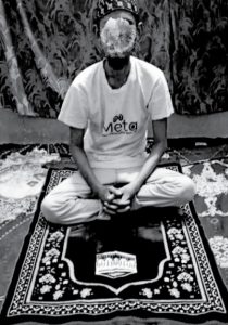 A young man sitting on a prayer mat.